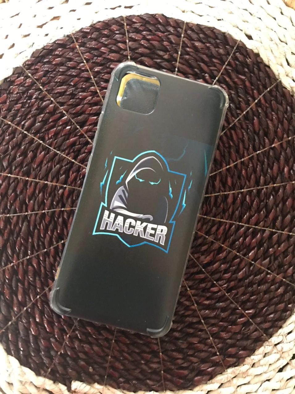 Case anticrack bening dengan cetakan logo sosok berkerudung bertuliskan HACKER di atas alas anyaman